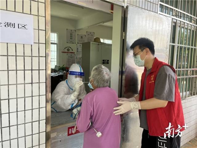 現(xiàn)場志愿者幫助行動不便群眾接受核酸檢測。
